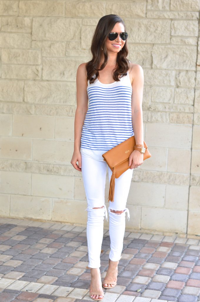 A blue and white stripe tank with white distressed jeans and a saddle brown monogrammed clutch.