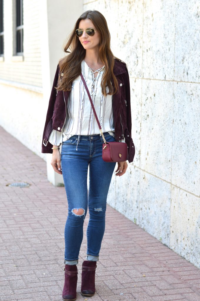 Burgundy suede moto jacket over a lace up striped top with burgundy moto boots
