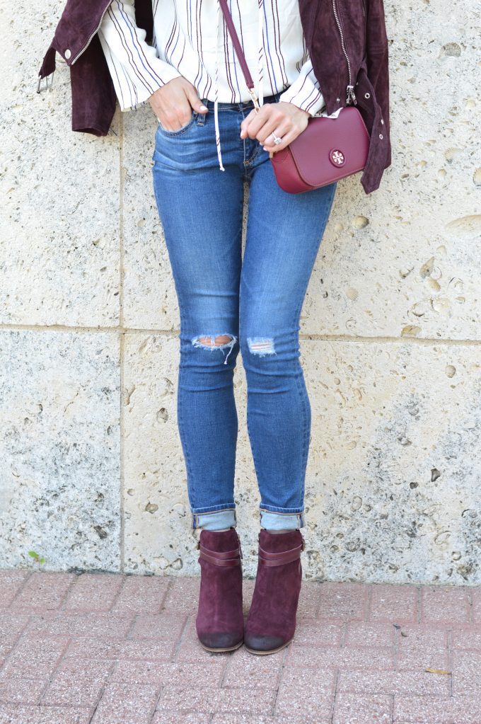 A striped lace up top worn with distressed jeans, burgundy moto booties and a burgundy cross body bag