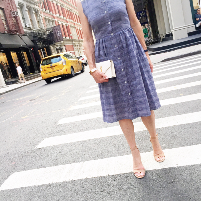 A blue shirtdress with a white clutch and nude sandals on a New York City street during Fashon Week. 