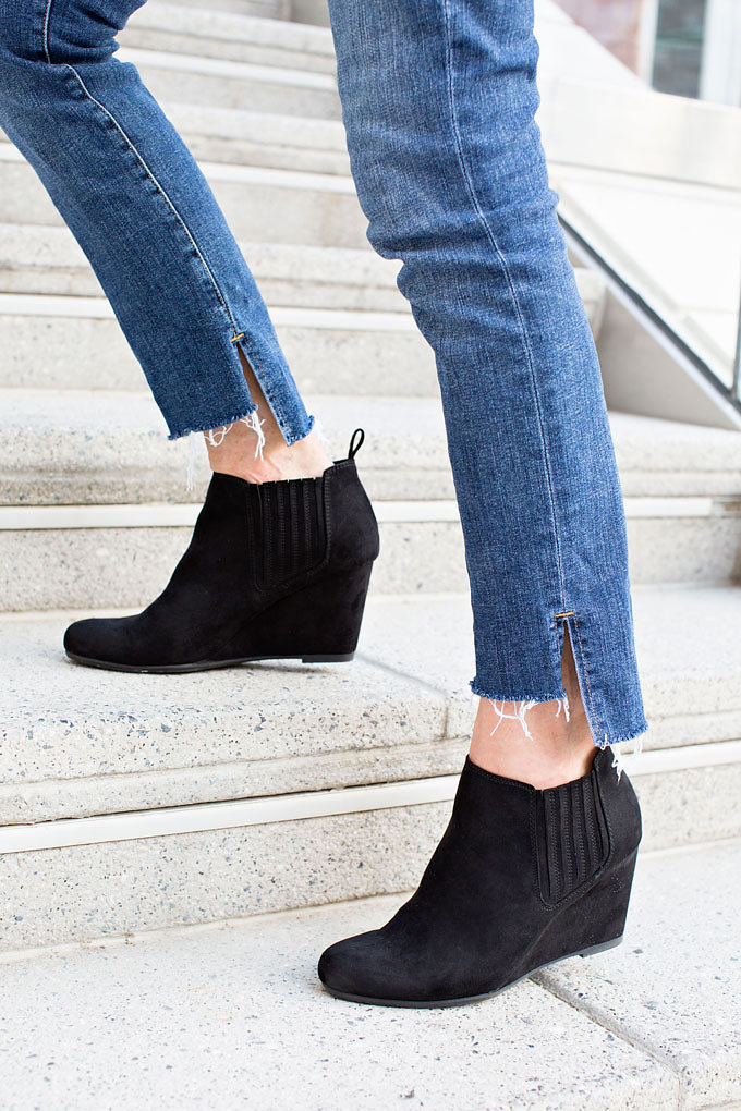 Jeans with an uneven frayed hem and black suede wedge booties.