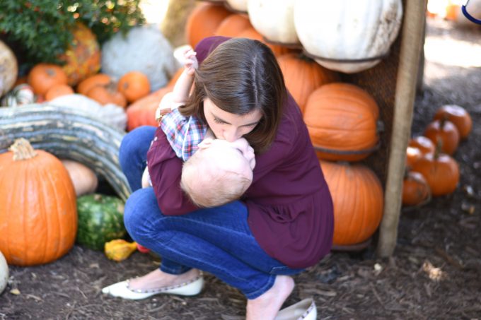 mother kissing baby in a pumpkin patch