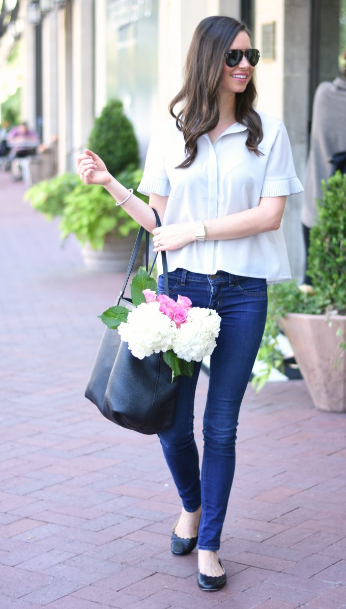 light grey short sleeve blouse with jeans and a black tote bag
