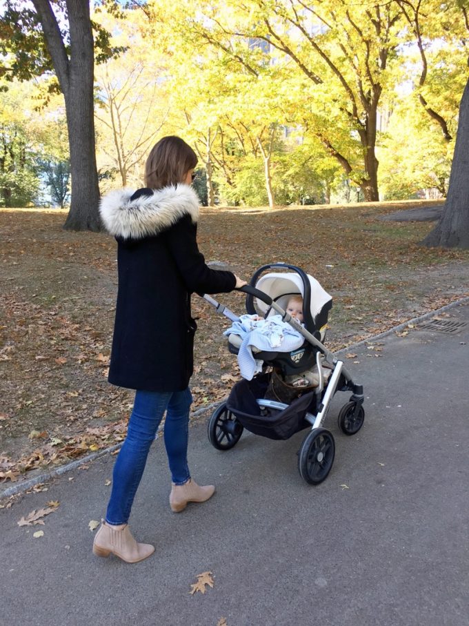 mom in black coat with fur trim pushing baby stroller