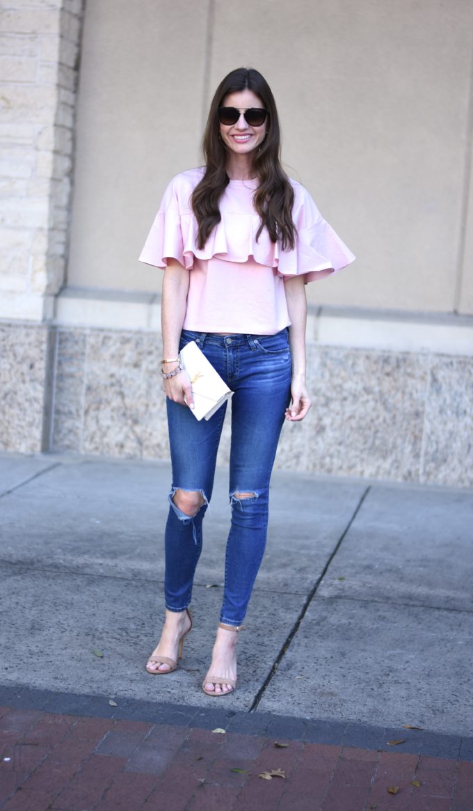 blush pink ruffle top with distressed jeans and white clutch