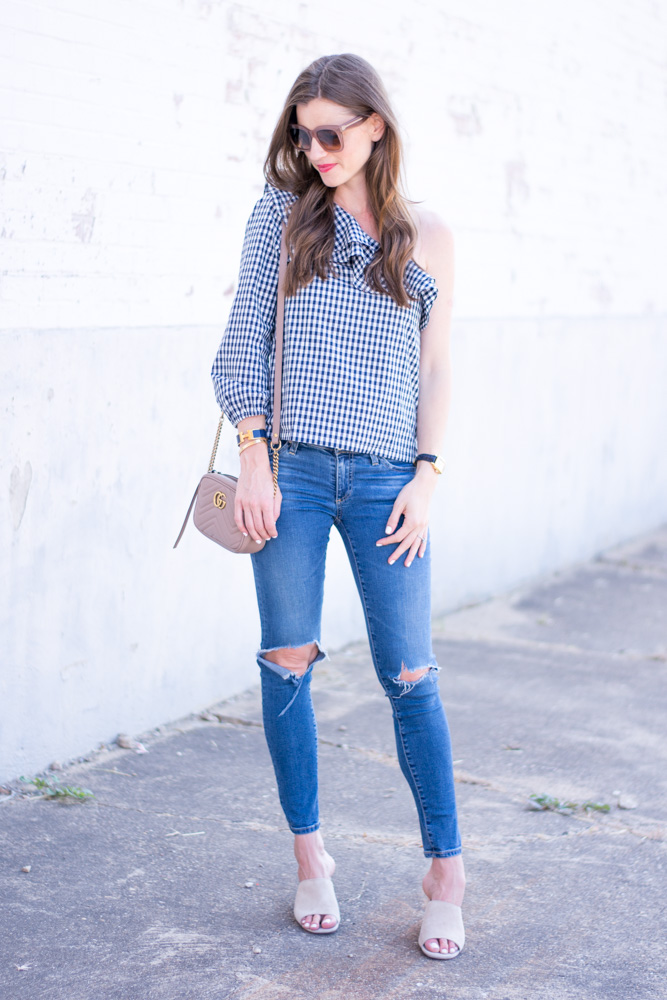 one shoulder gingham top with distressed jeans nude handbag and mules