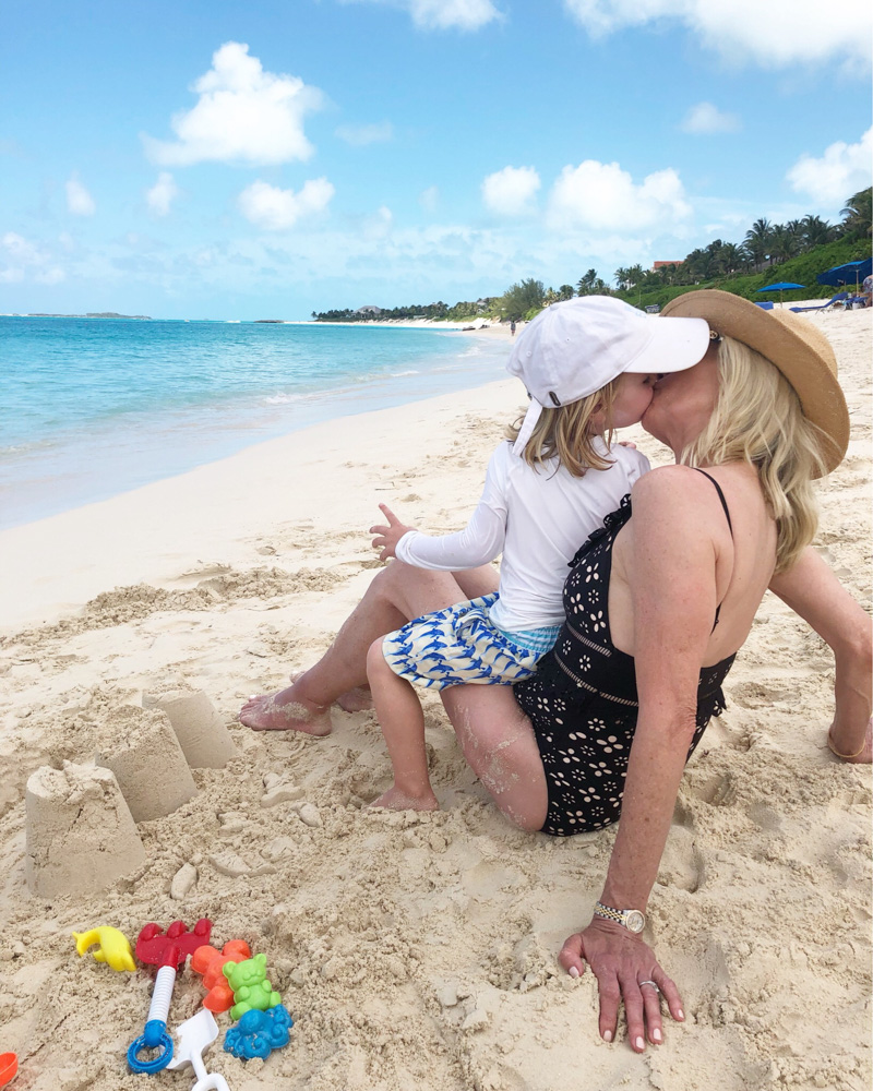 toddler boy kissing grandmother on the beach