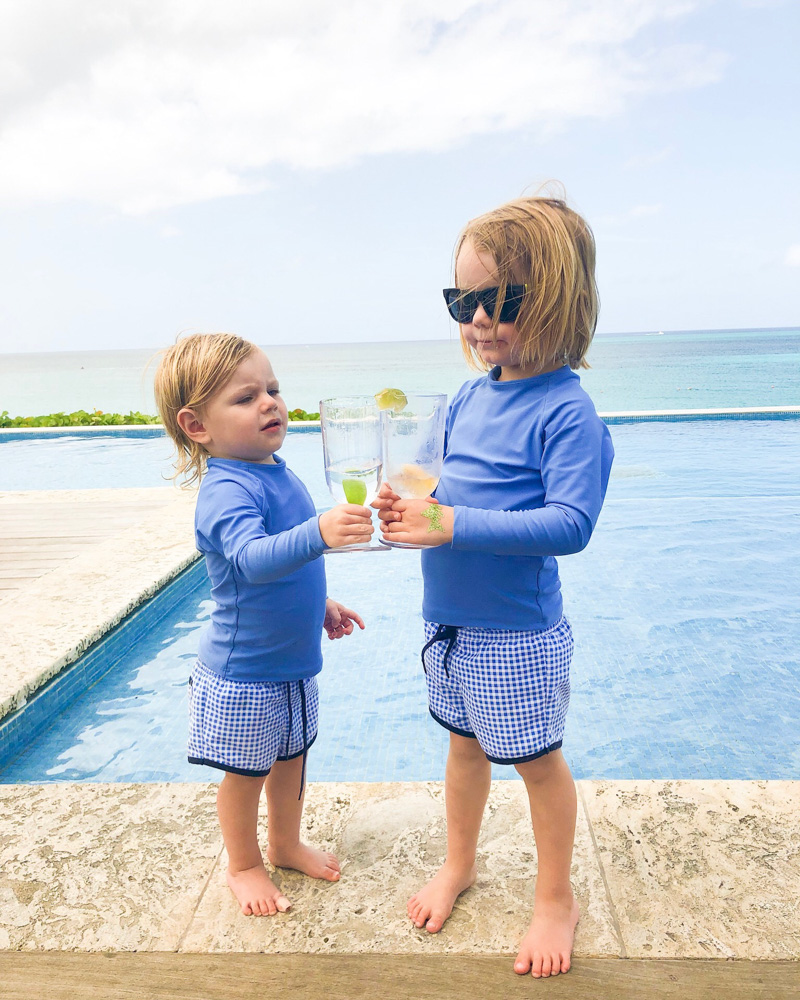 toddler boys toasting with water glasses poolside