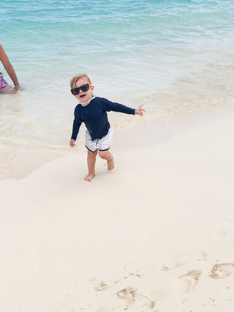 toddler boy walking on the beach