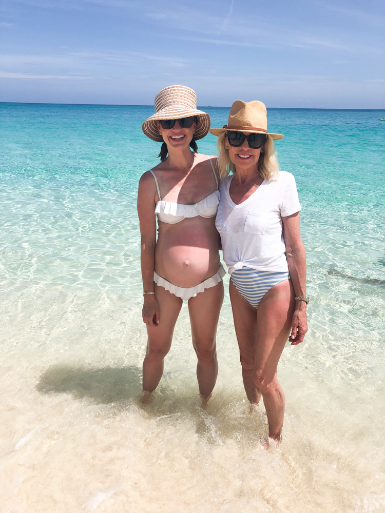 mom and daughter standing on ocean shore