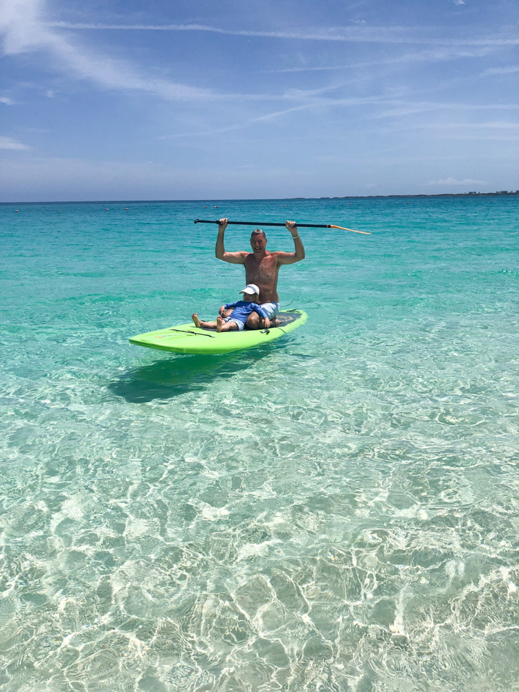 man and toddler seated on paddleboard