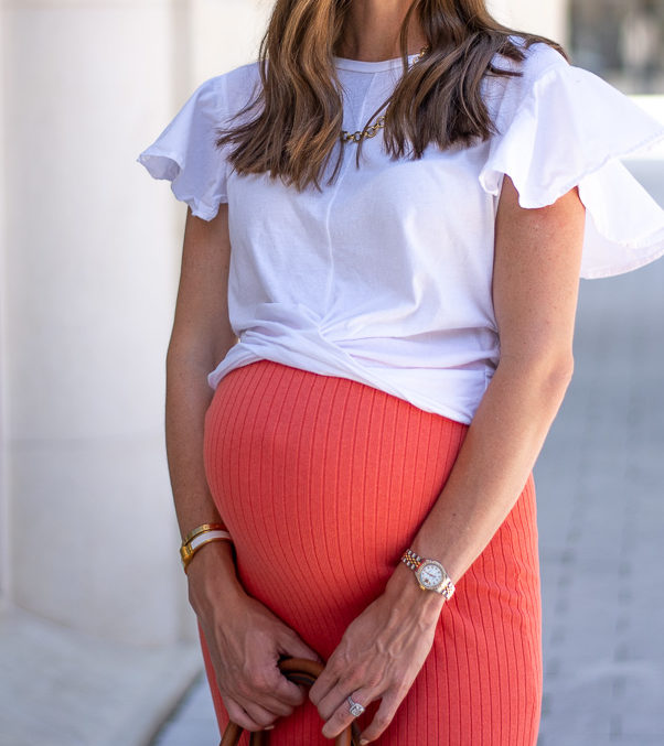 pregnant woman white ruffle sleeve top coral skirt