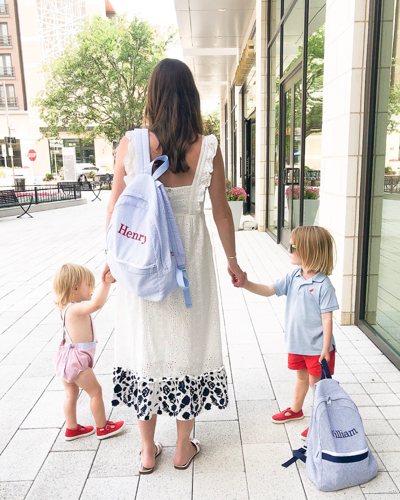 mom walking with toddler boys carrying matching backpacks