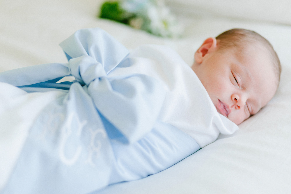 newborn baby in blue bow swaddle