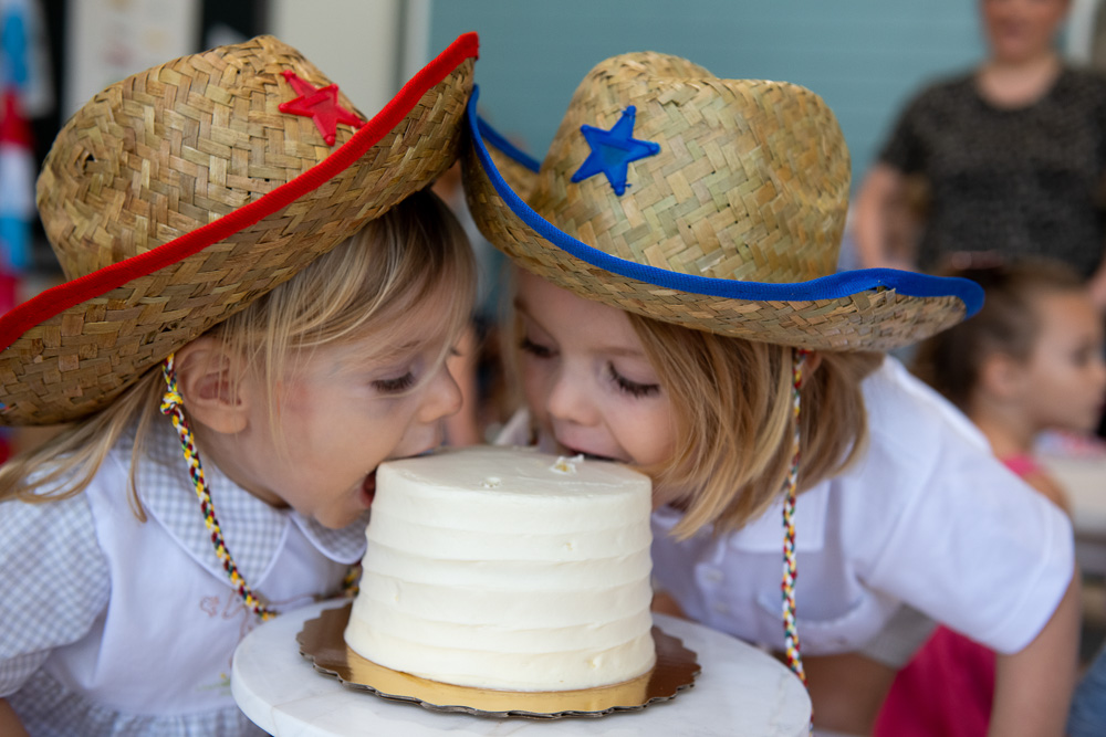 two toddler boys taking bites out of birthday cake