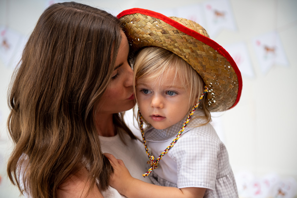 mom kissing toddler boy in cowboy hat