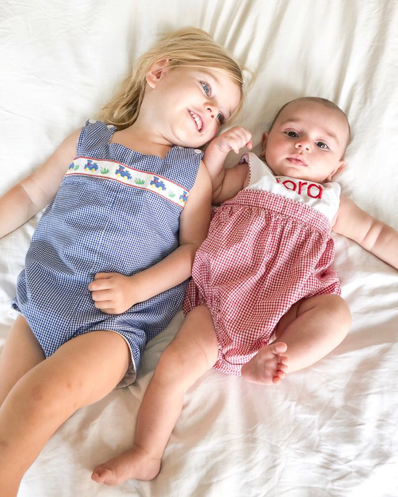 toddler and baby laying on bed