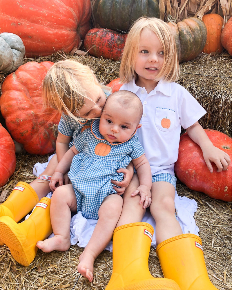 two toddlers with baby brother at pumpkin patch