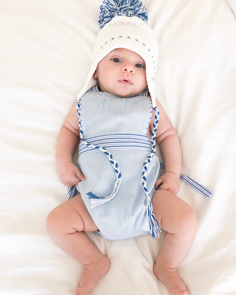 baby boy in striped sunsuit knit pompom hat