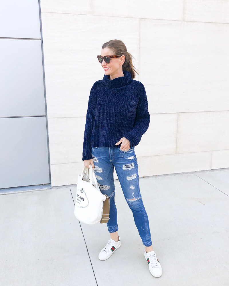 woman in blue sweater and distressed jeans