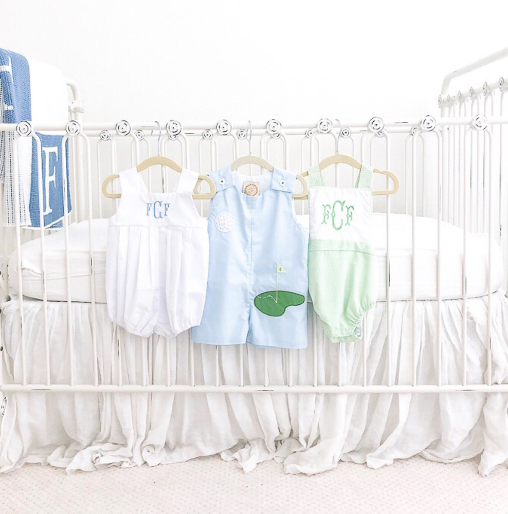 baby boy clothes hanging on crib
