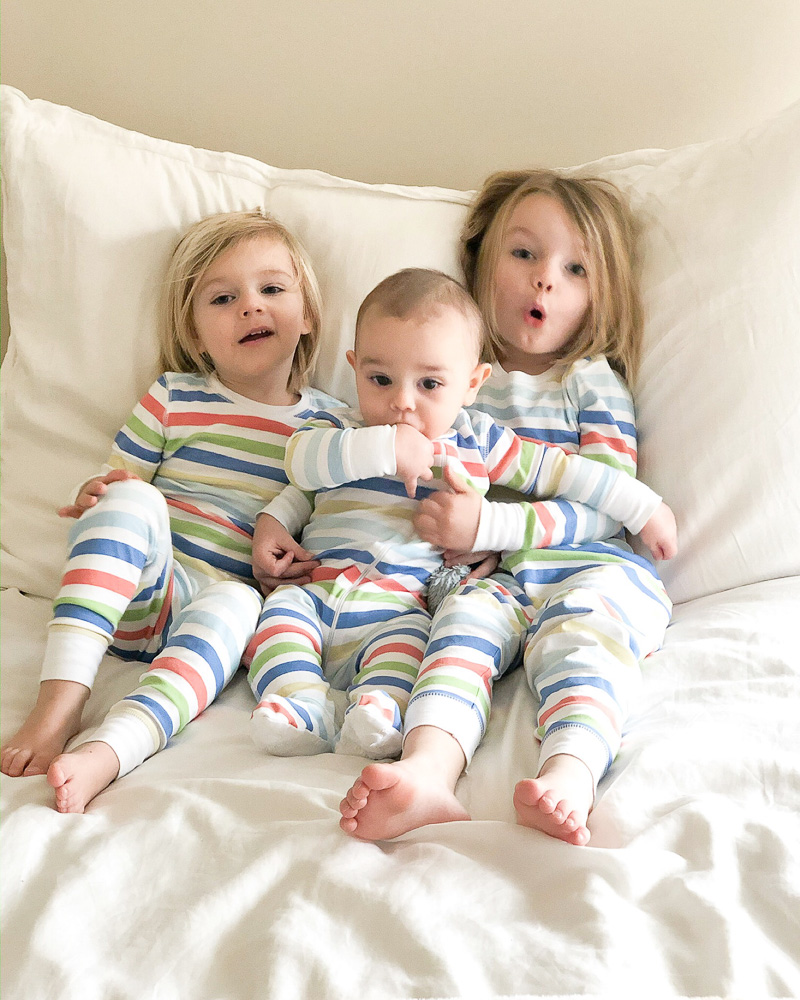 three toddler boys in bed in striped pajamas