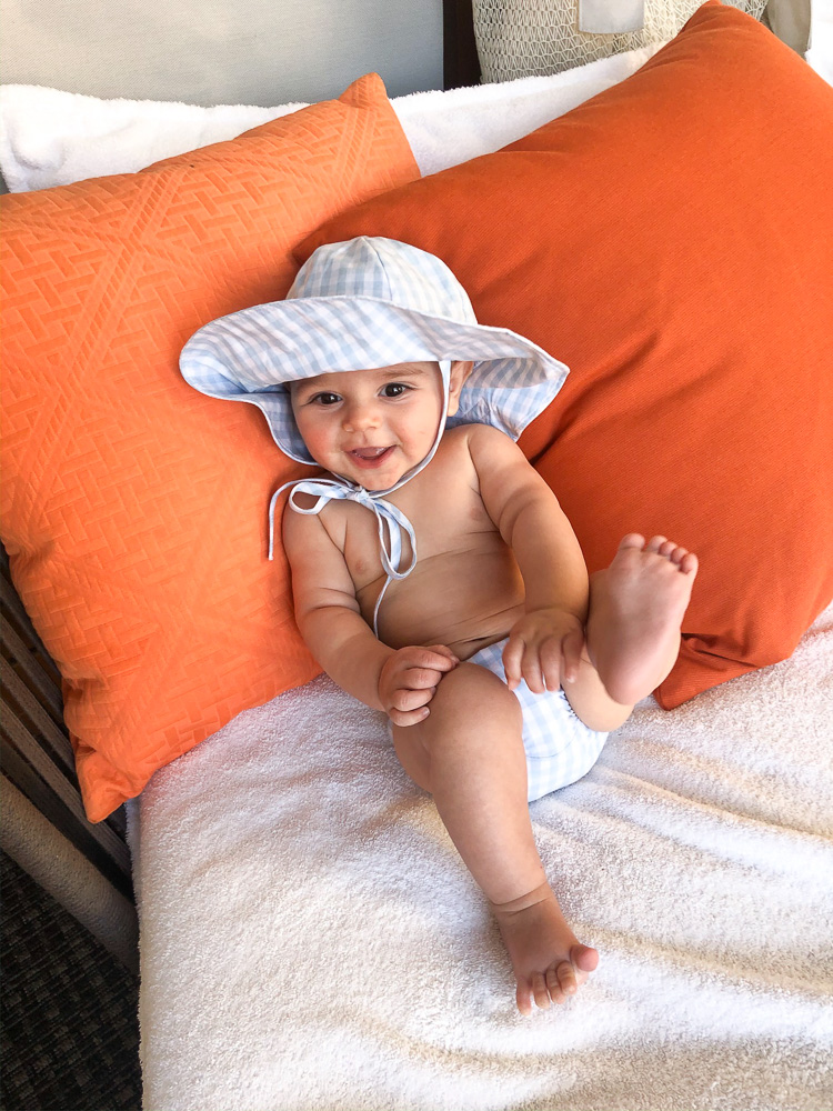 baby in gingham sun hat on lounge chair