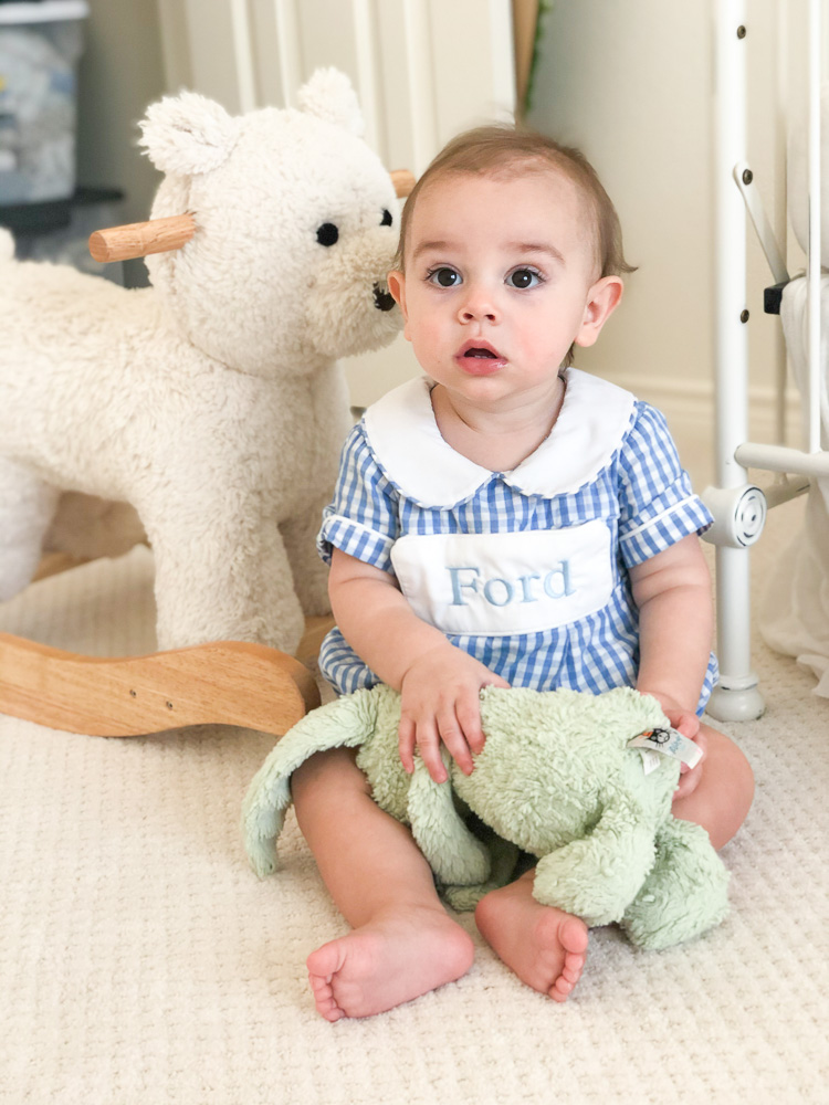 baby sitting on floor with green bunny