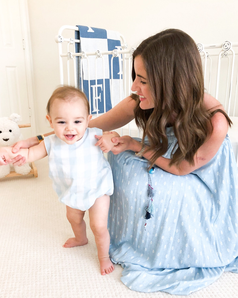 mom with standing baby in nursery