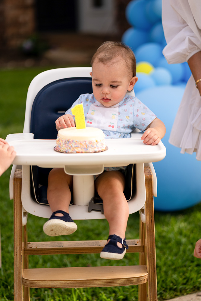 baby in highchair with first birthday cake