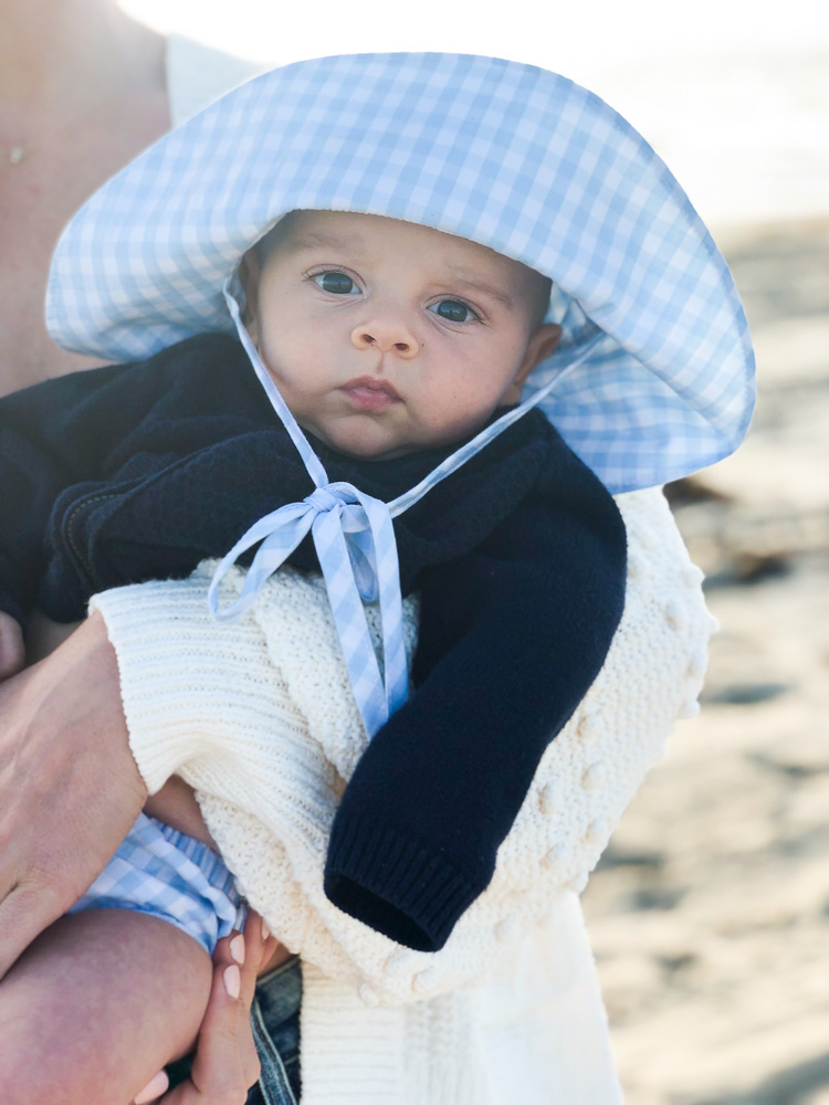 baby in gingham hat at the beach