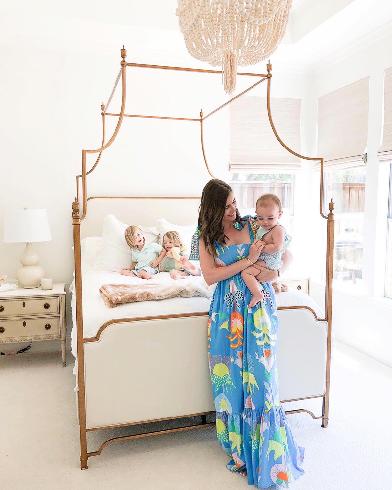 mom holding baby in front of canopy bed