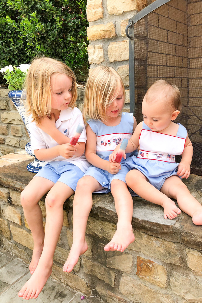 three little boys eating popsicles outside