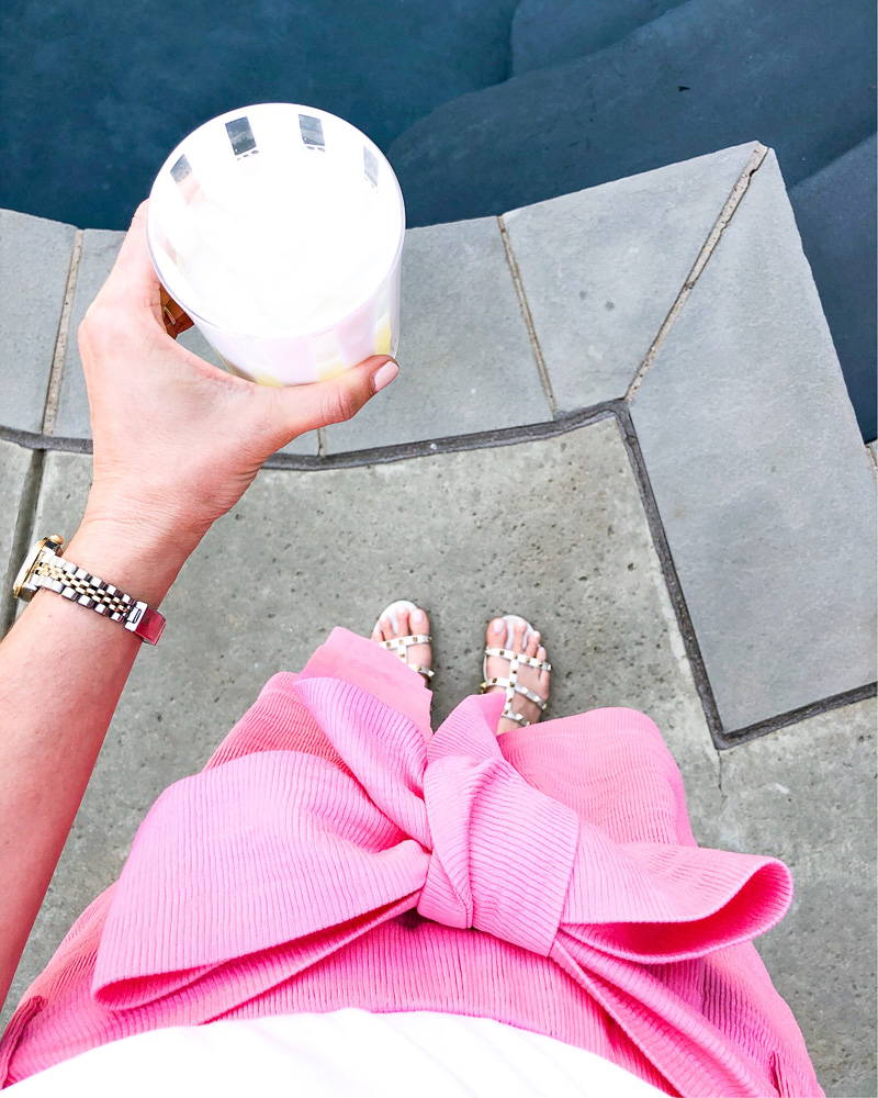 pink shorts with bow holding margarita by pool