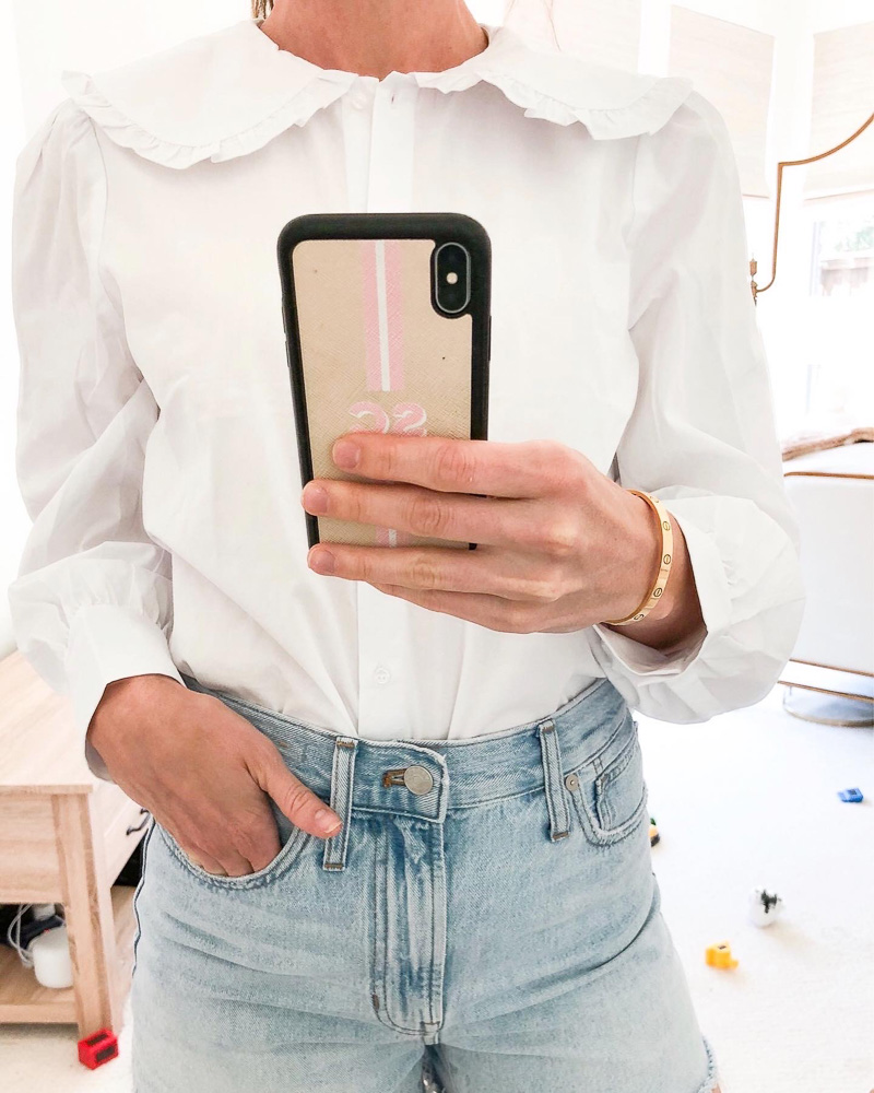 woman in mirror wearing white blouse with large collar