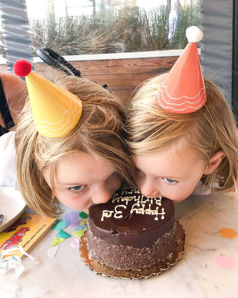 two brothers in party hats biting into birthday cake