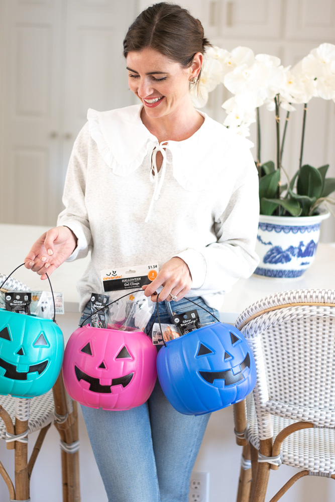 woman holding three colorful pumpkin pails