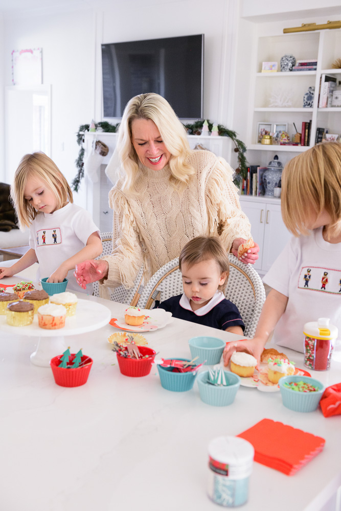 grandmother with three toddler boys decorating holiday cupcakes