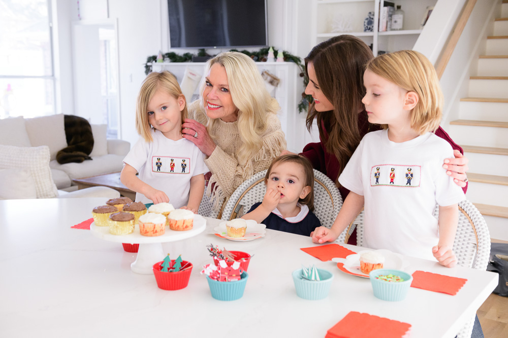 mom and grandmother with three toddler boys decorating cupcakes