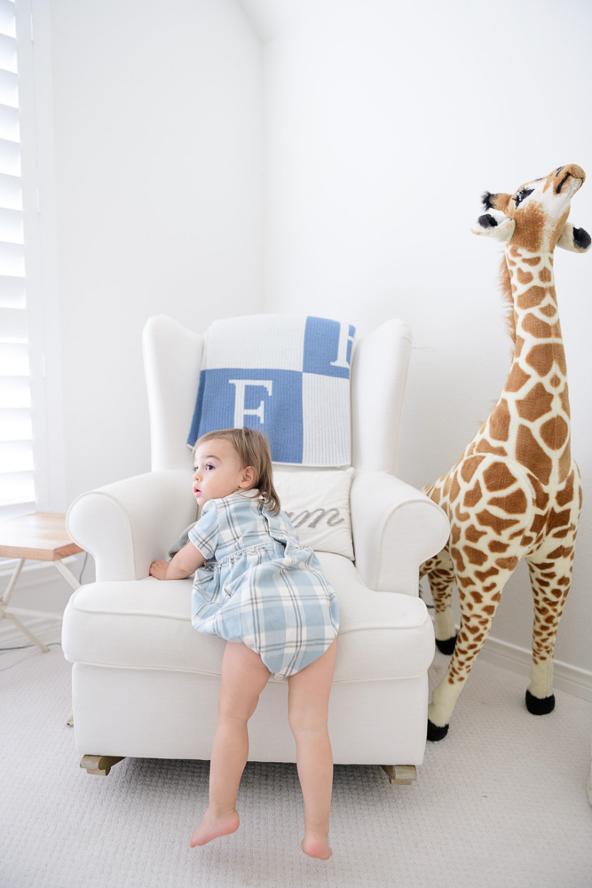 baby boy in nursery with stuffed giraffe