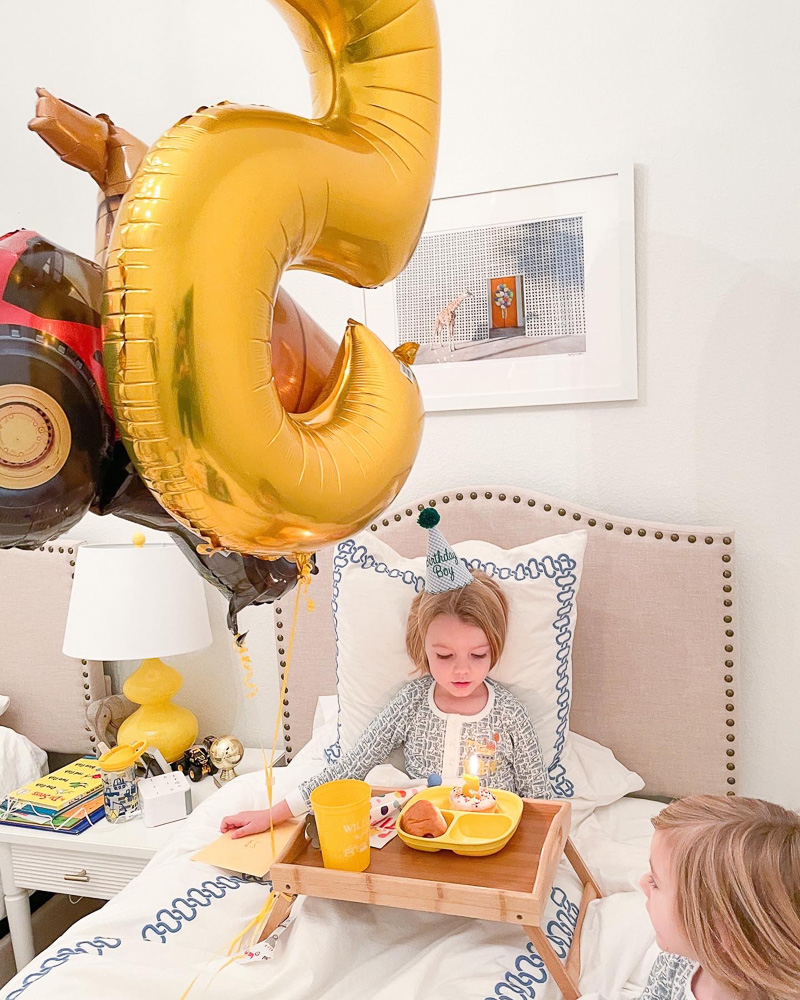 boy in bed with 5 balloon and breakfast in bed