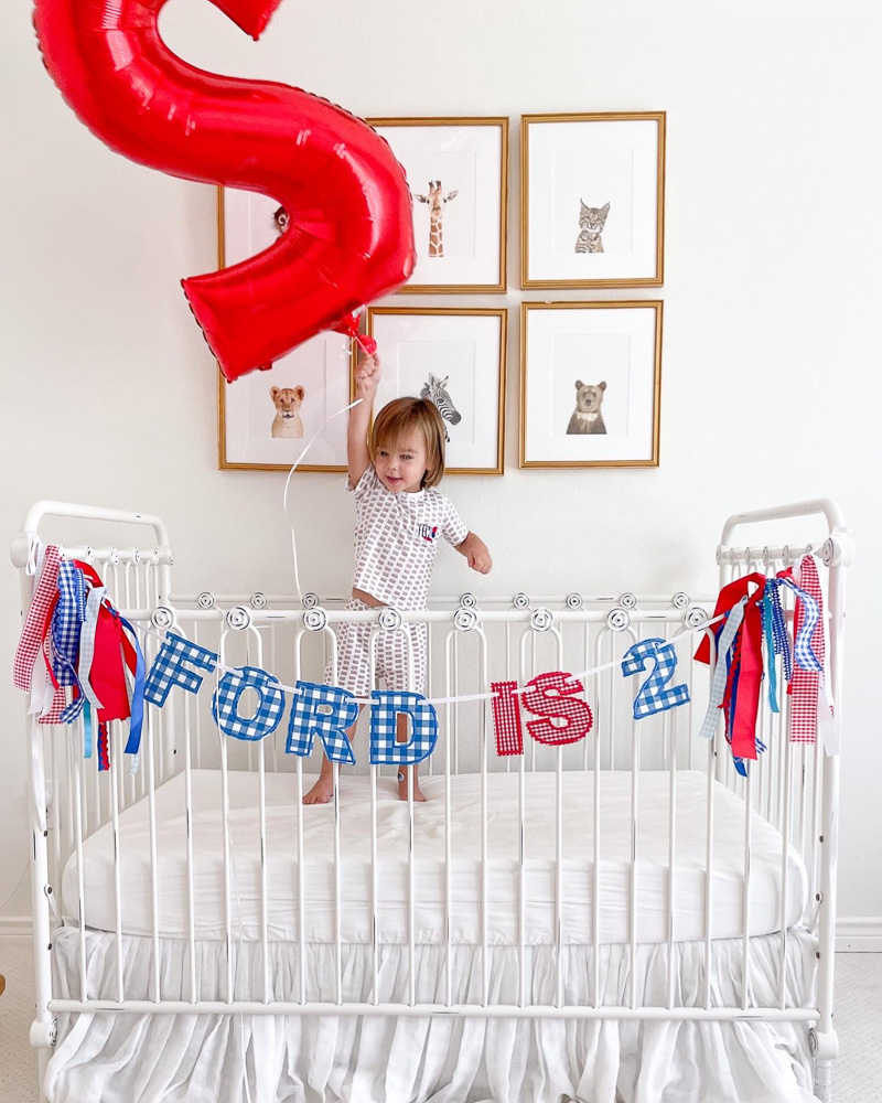 baby in crib with birthday banner and balloon