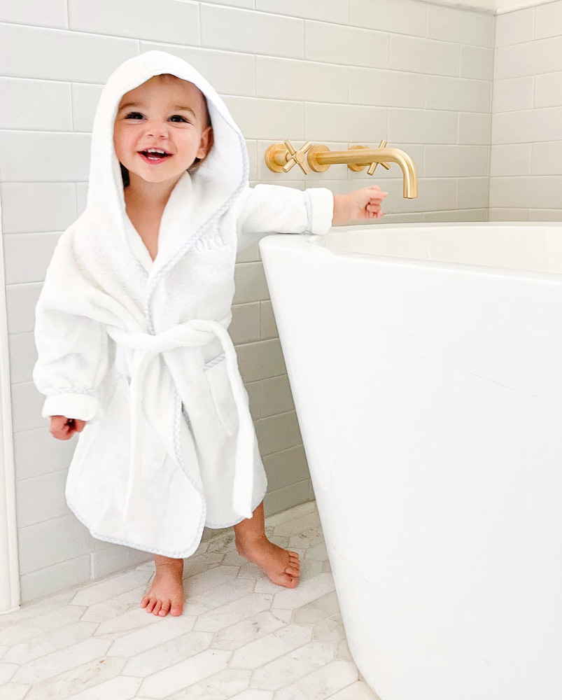 toddler in hooded robe by bathtub