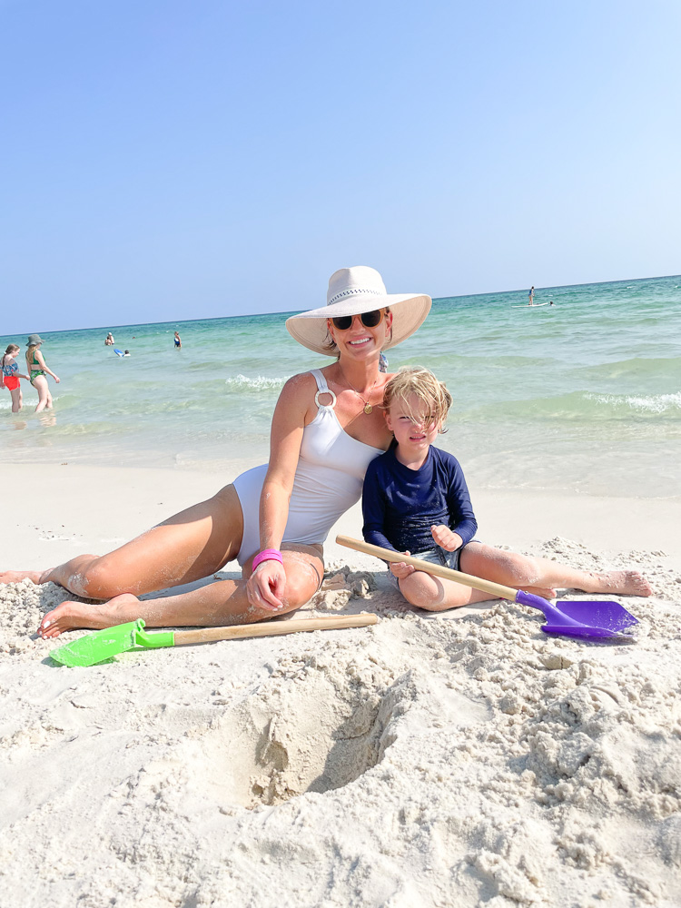 mom and son sitting on the beach with sand shovels