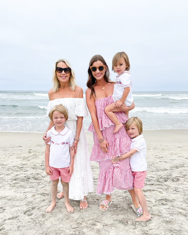 two women standing on beach with three little boys