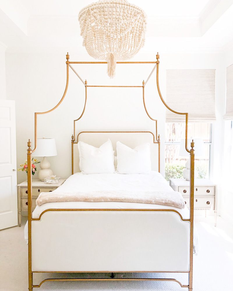 master bedroom with brass canopy bed and chandelier