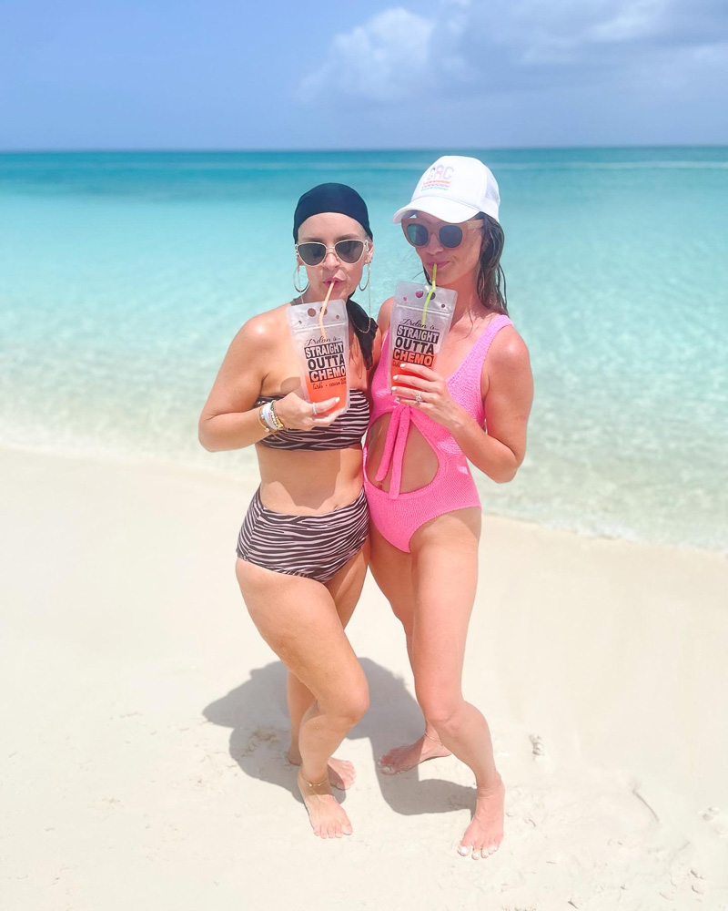 two women with drinks in swim suits standing in the ocean