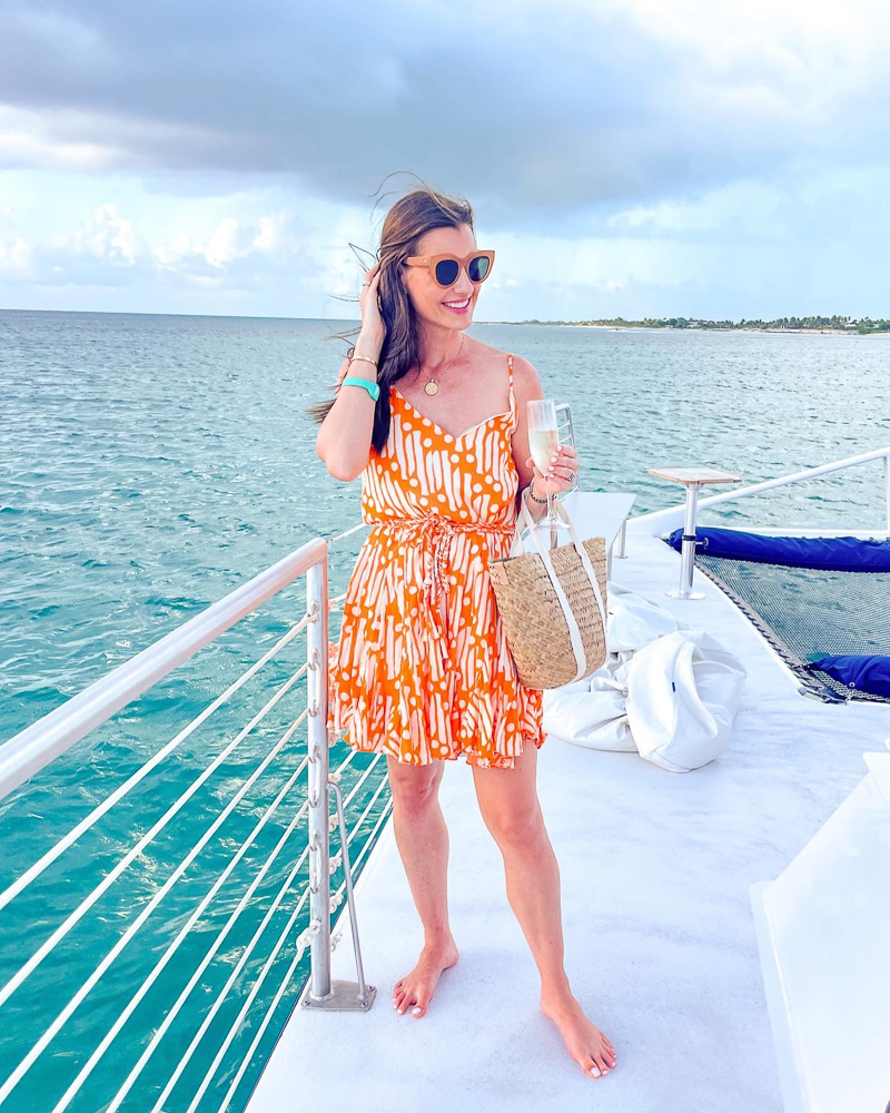 woman in orange and white mini dress on boat deck at sea