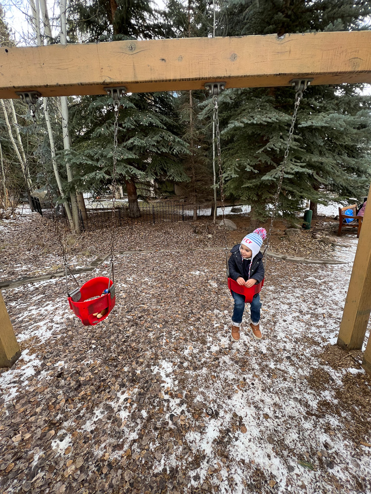 toddler swinging in snow covered park