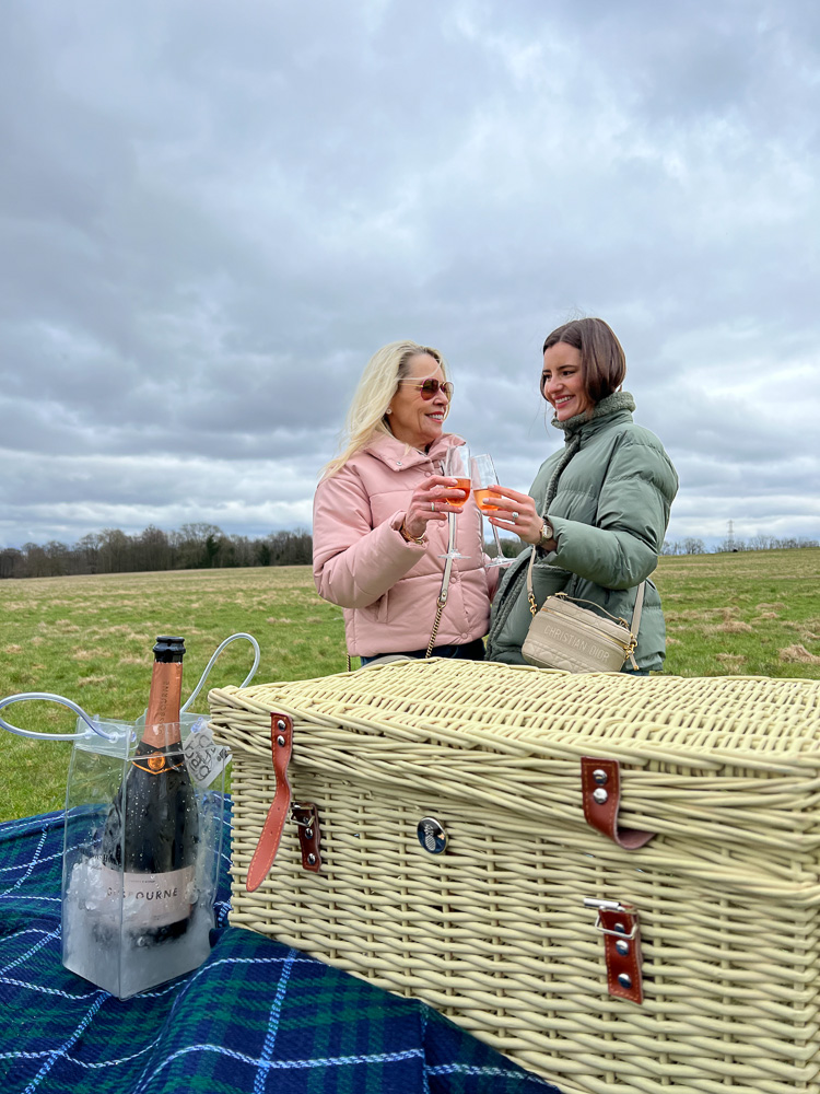 two women toasting with champagne at a picnic